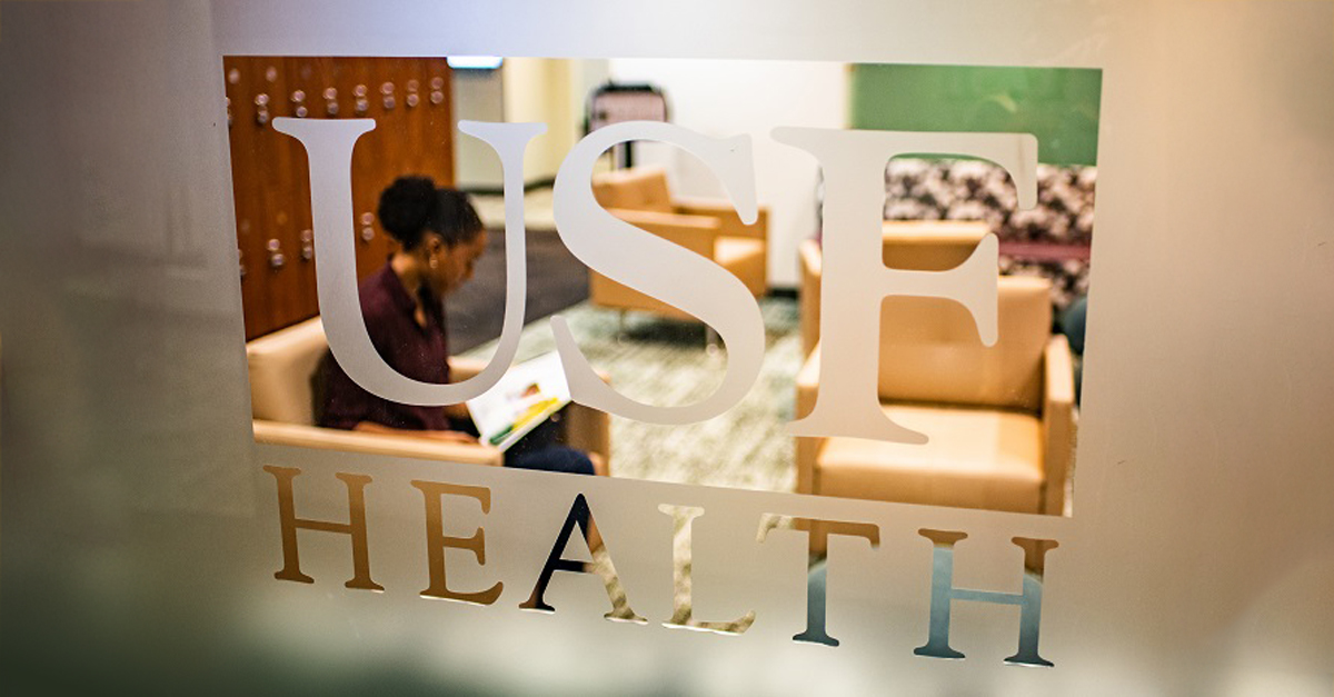 Students reading behind a glass with a USF logo