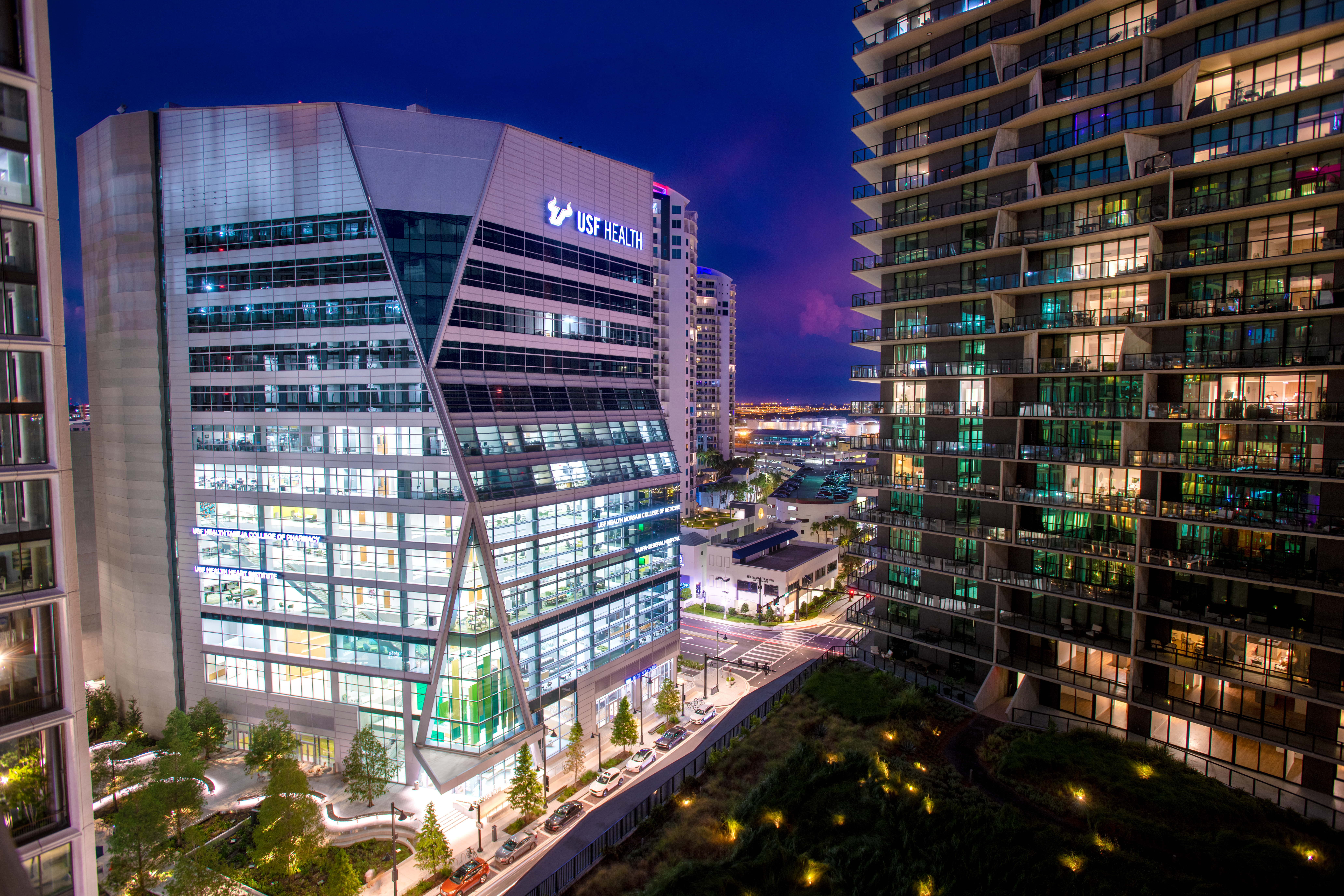 Ariel shot of the USF Health Downtown Tampa building at night showing light illuminating from inside of the buildings surrounding the city.