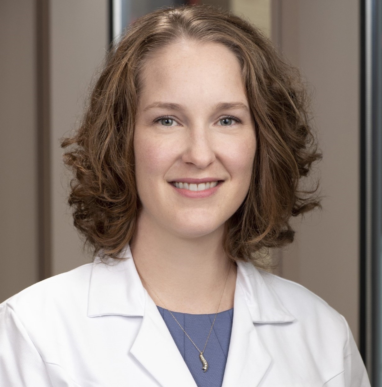 Kay Everett smiling wearing a blue blouse under a medical white coat