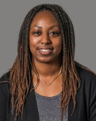 Makebba Spears smiling wearing a grey blouse and black blazer with a silver necklace