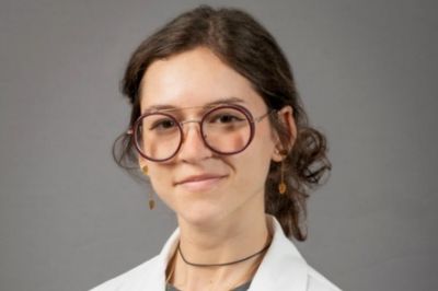 Claudia Cedeno Kwong smiling wearing a USF health branded medical white coat