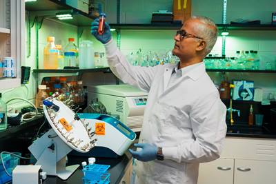 USF Health medical recearcher holding up a sample in a laboratory filled with medical testing equipment