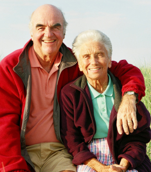 Elderly man and woman sitting together outside.