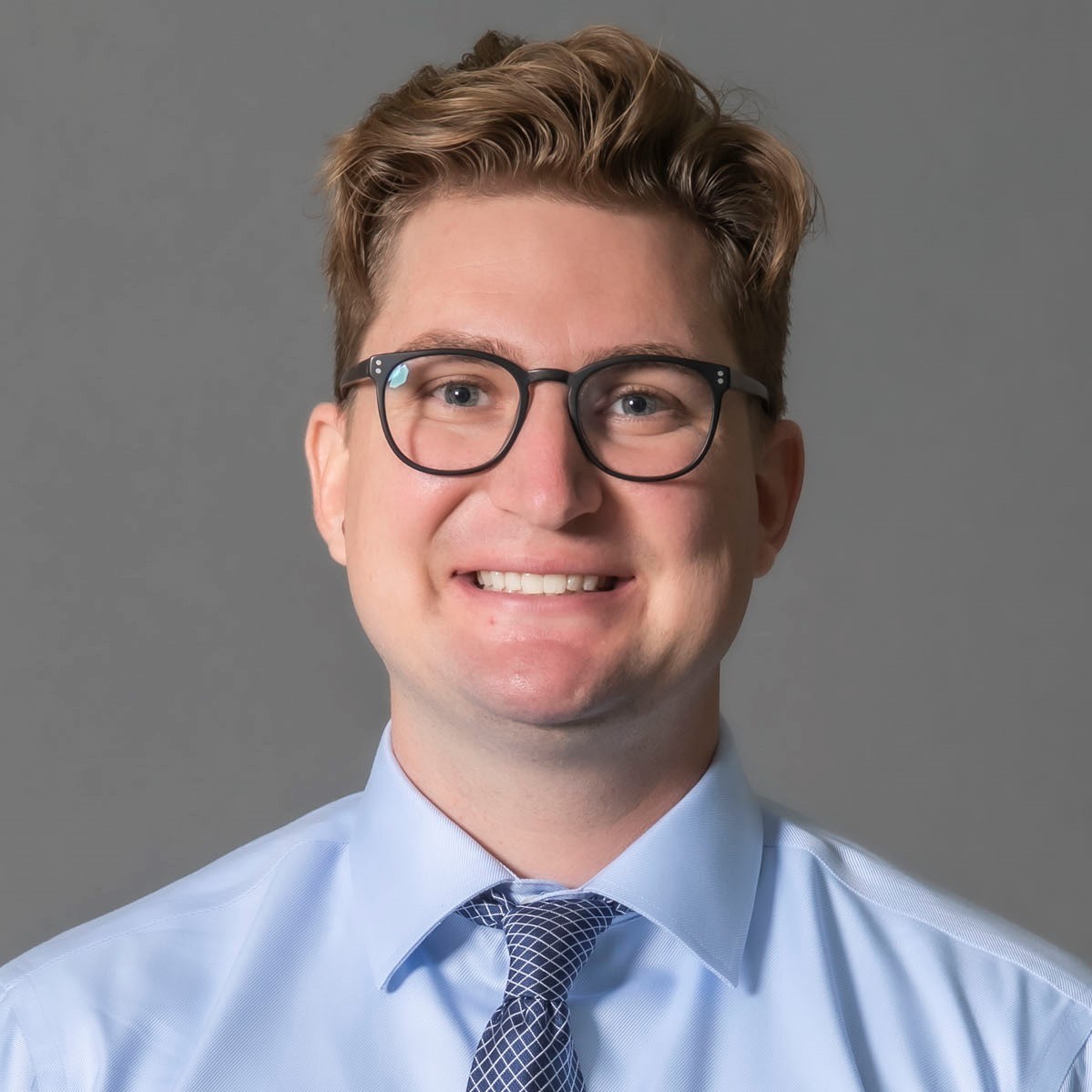 A headshot of Dr. Webb in a blue button down and tie