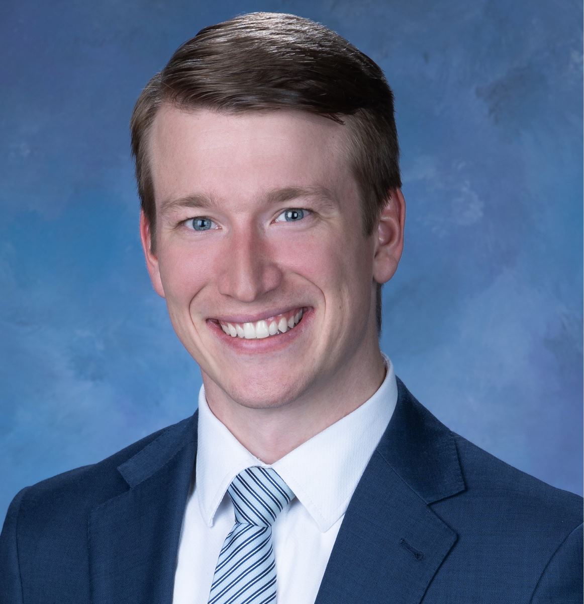 Dr. Blaylock wearing a blue suit jacket, white collar shirt, blue striped tie
