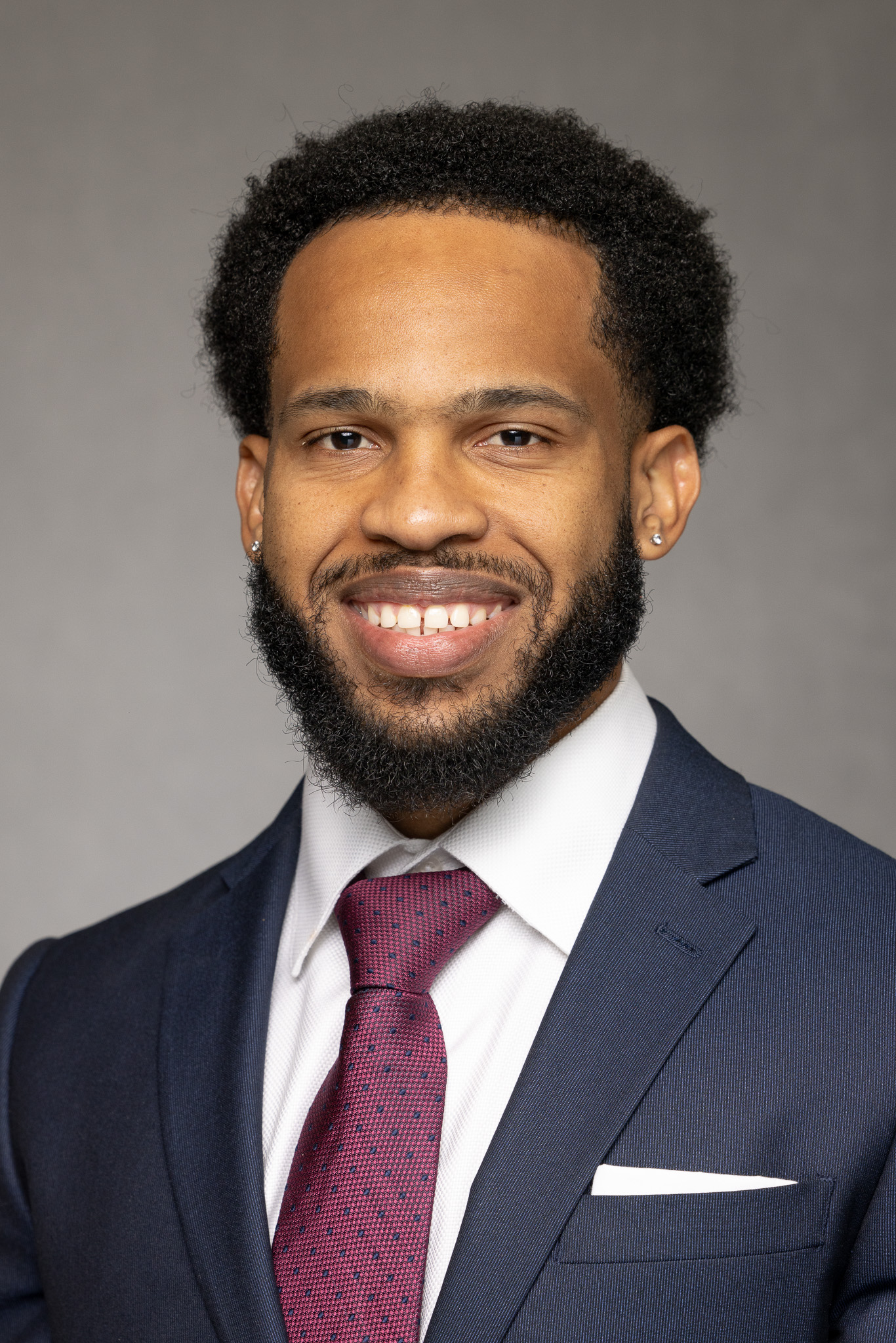 headshot of Bartley in suit with purple tie