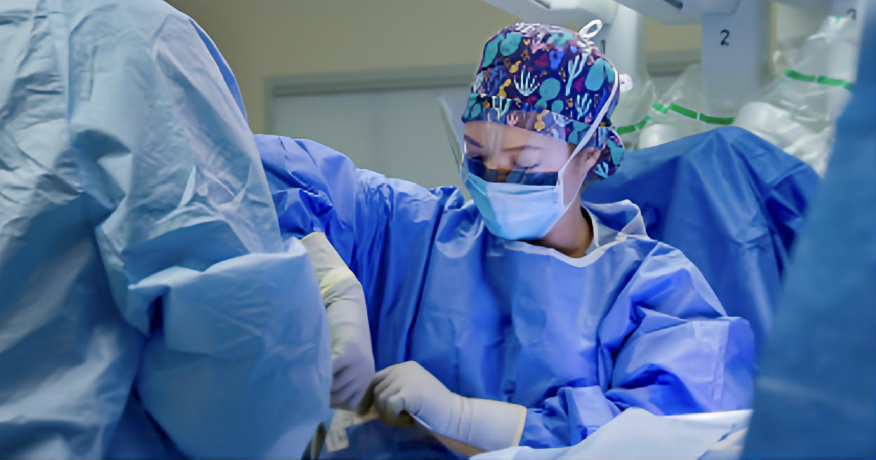 Medical personnel in blue scrubs sitting conducting surgery
