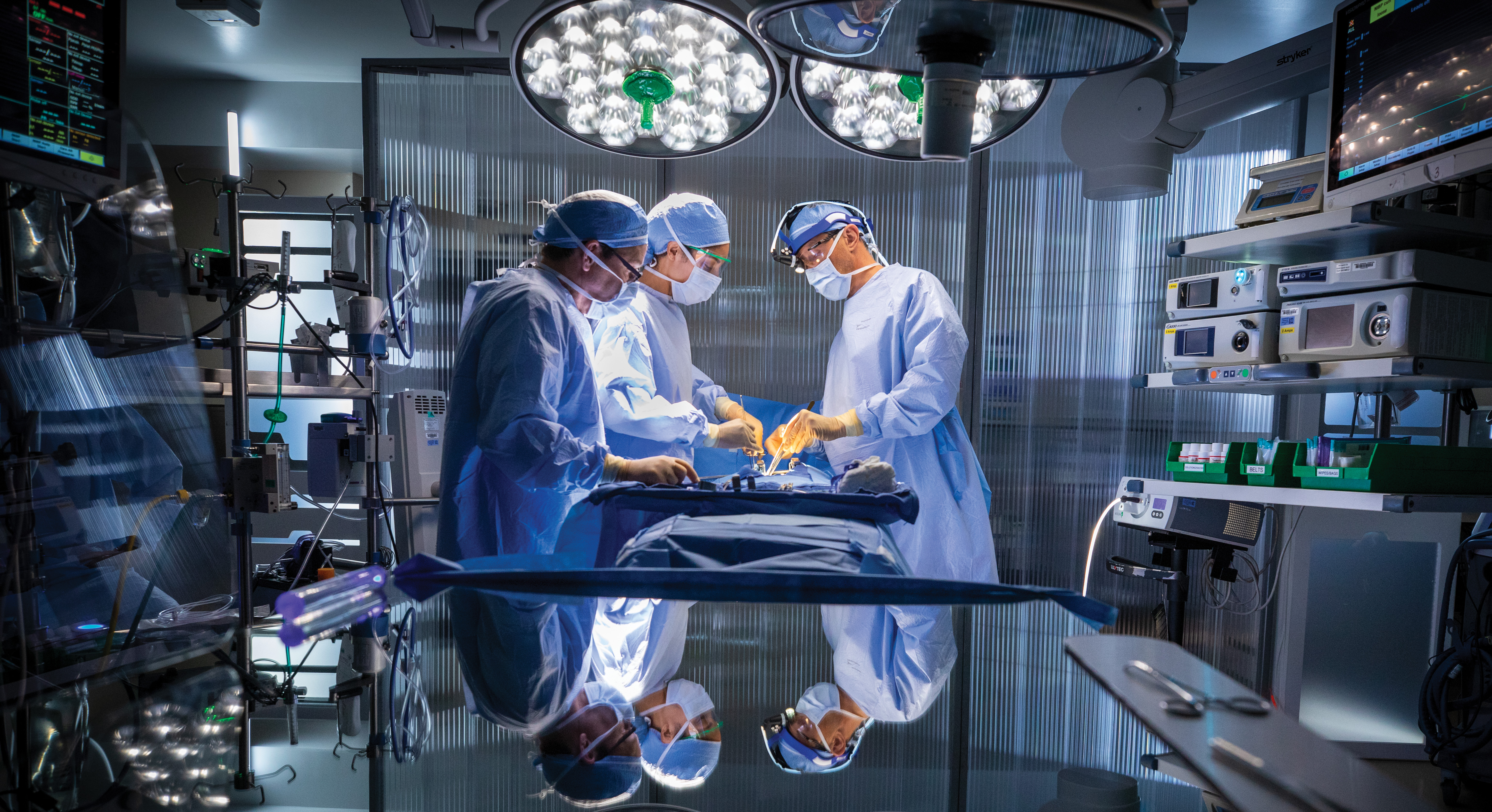 Surgeons conducting surgery in a medical room wearing blue surgery gear 