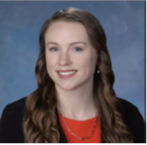 Emelia Watts smiling with a red blouse and black blazer