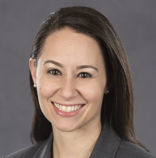 Karyn Gerstle smiling wearing a grey shirt with a grey background