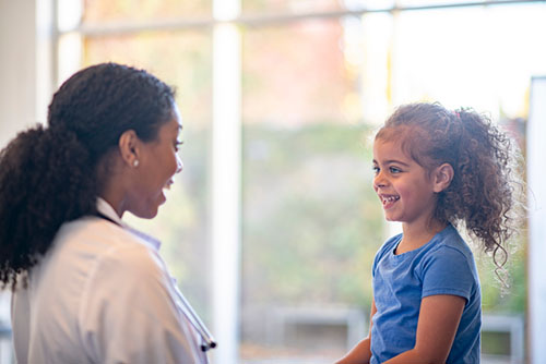 A Doctor is meeting with a pediatrics patient and she appears happy.