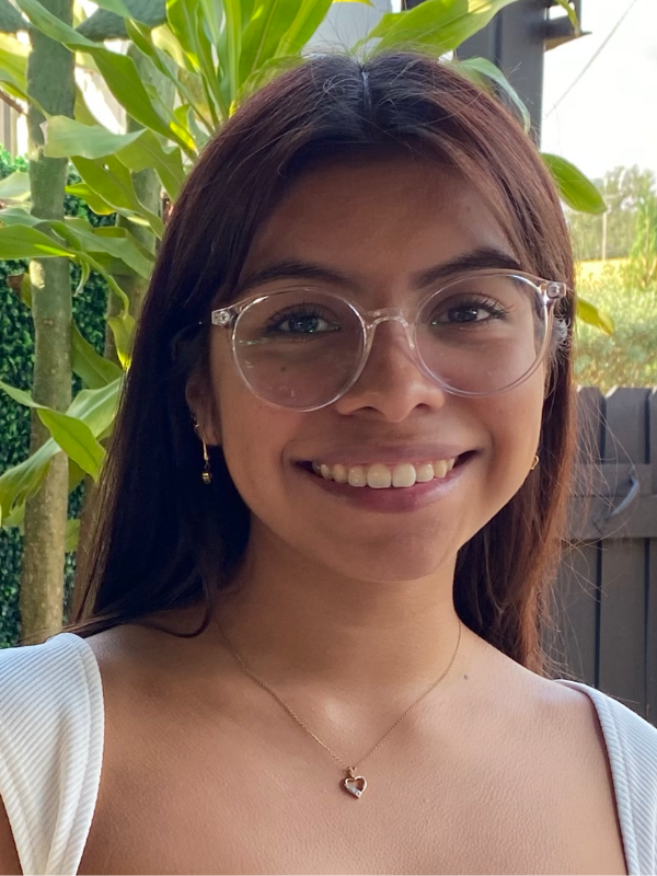 Headshot of Angelica Rios posed in front of greenery