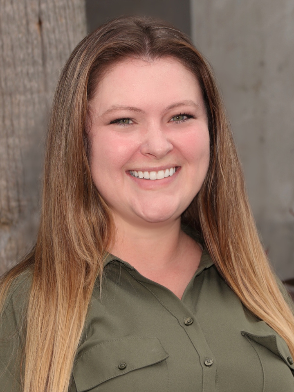 Headshot of Liz Bannon smiling in front of an outdoor backdrop.
