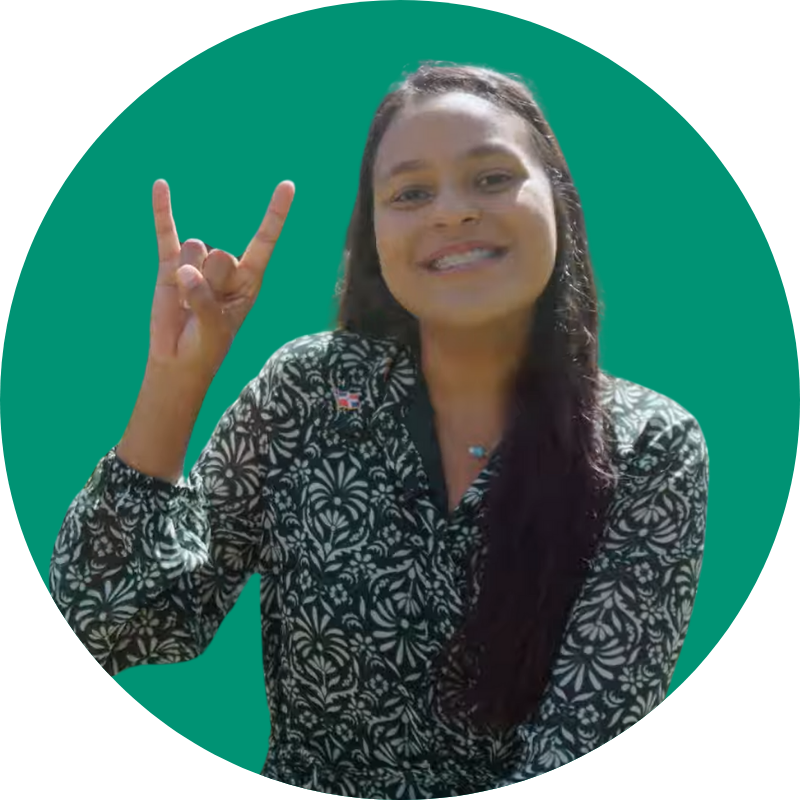 Audry Belén Valdez holding up the "Go Bulls" hand symbol in front of a green background