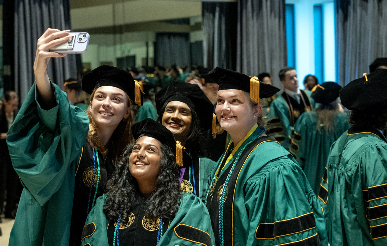 USF Health medical student wearing cap and gowns at commencement, smiling for a selfie