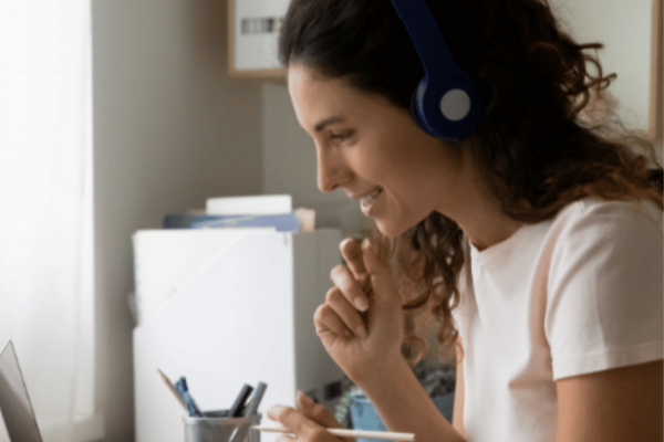 A woman wearing headphones and looking at her computer.