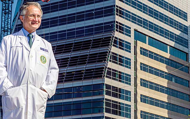 Dr Charles Lockwood looking out towards the sun with USF Health medical building in the background