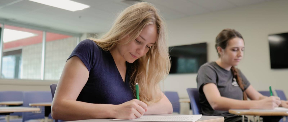 Two students taking an exam in a classroom setting.