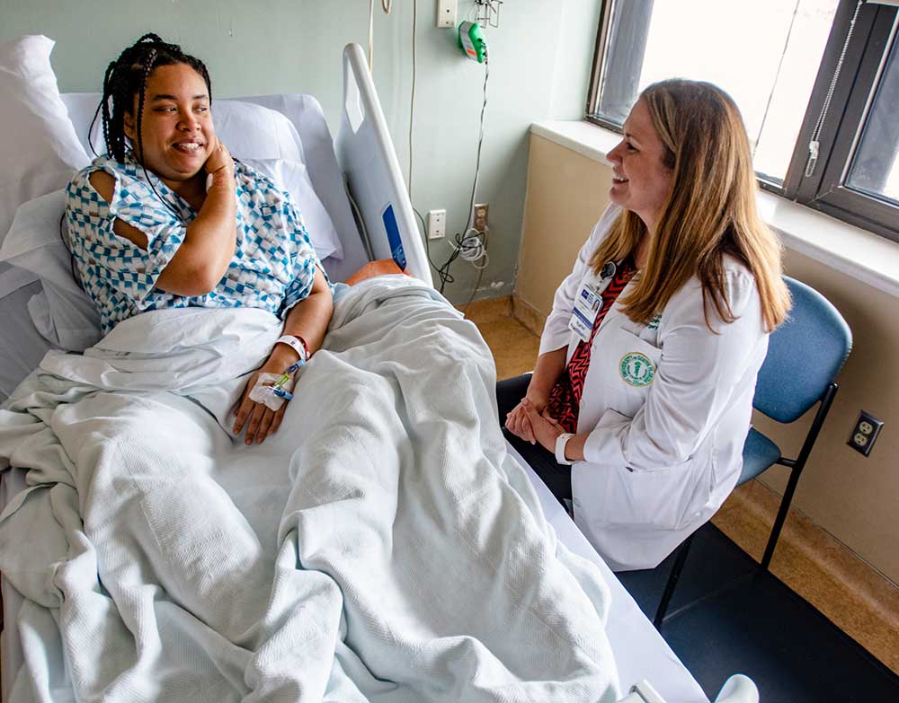 medical examination room with a smiling female patient in bed as her doctor smiles at her