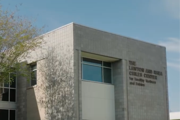 The exterior of the Lawton and Rhea Chiles Center building in front of a blue, morning sky.