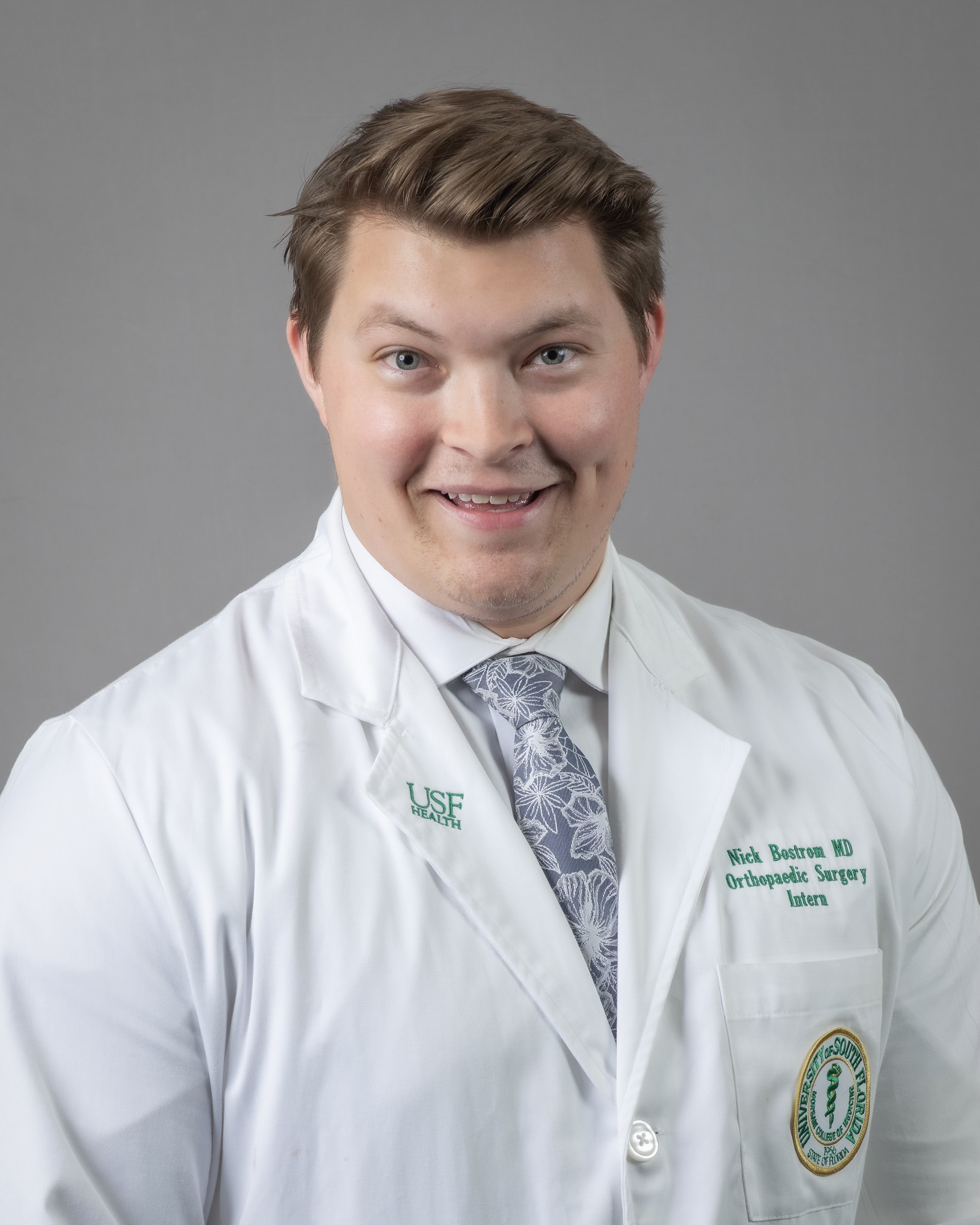 Nick smiling wearing a USF Health branded medical white coat