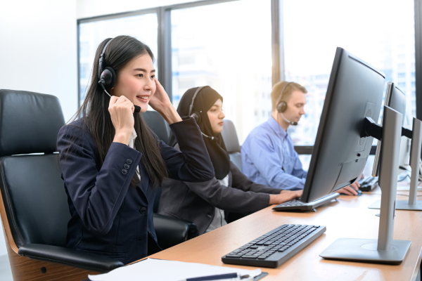 A group of people wearing headsets and working at their computers.