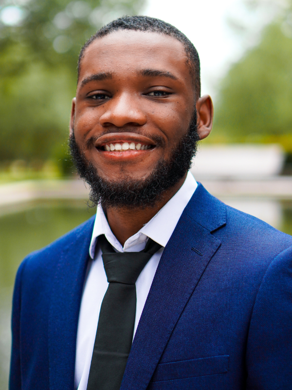 Headshot of Leomar White posed in front of greenery