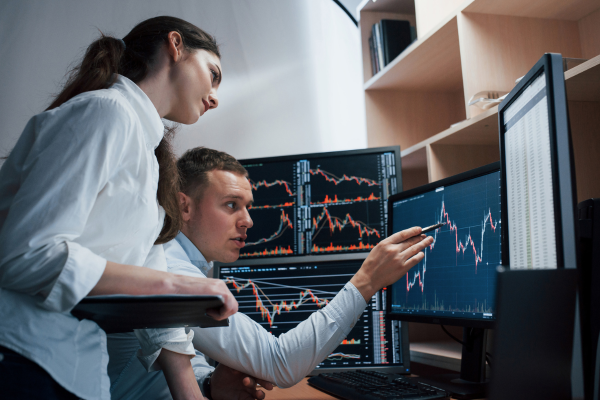 Two people looking at charts on a computer screen