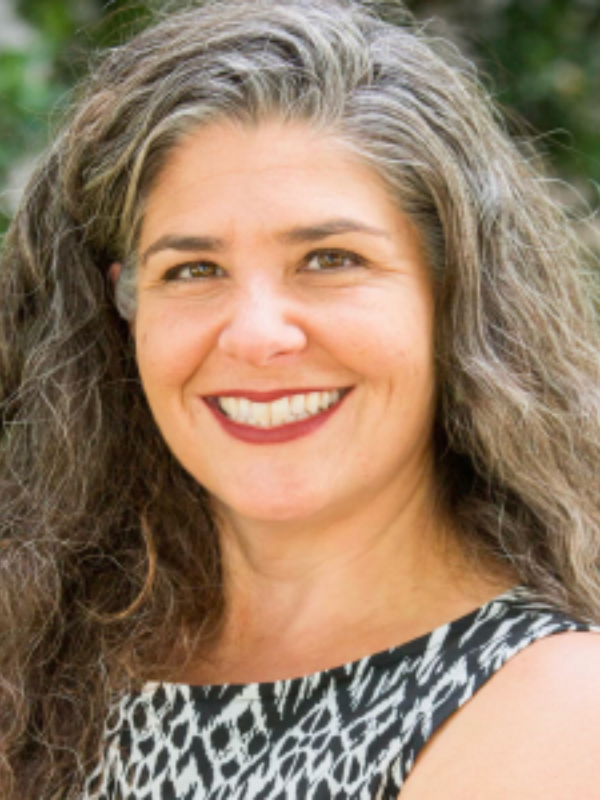 Headshot of Nicole Sutton posed in front of greenery