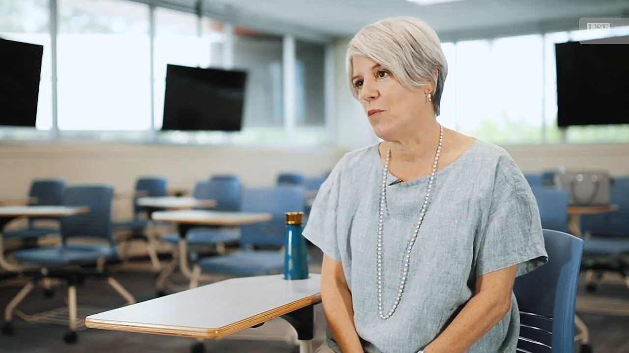 Dr. Claudia Parvanta sitting at a desk in a classroom