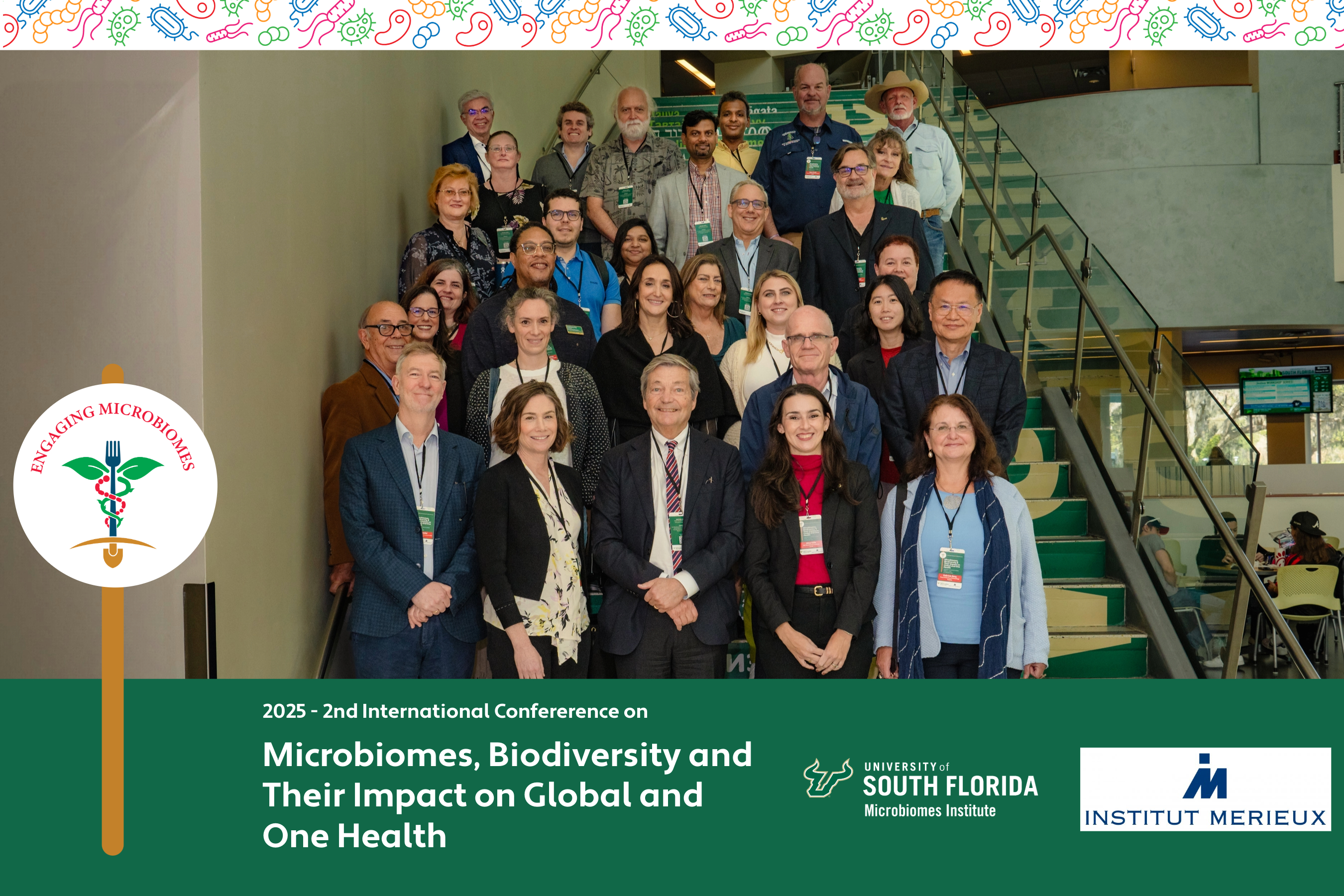 A diverse group of attendees at the 2025 International Conference on Microbiomes, Biodiversity, and their Impact on Global and One Health, standing together and smiling. The backdrop features a banner with the conference title and logos of sponsoring organizations. The participants represent various fields of study, showcasing the collaborative spirit of the event."