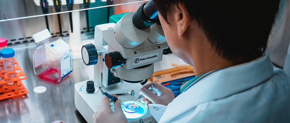 A doctor in a lab looking into a microscope. 