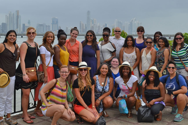 A group of students and faculty posing for a photo in front of the Panama skyline.