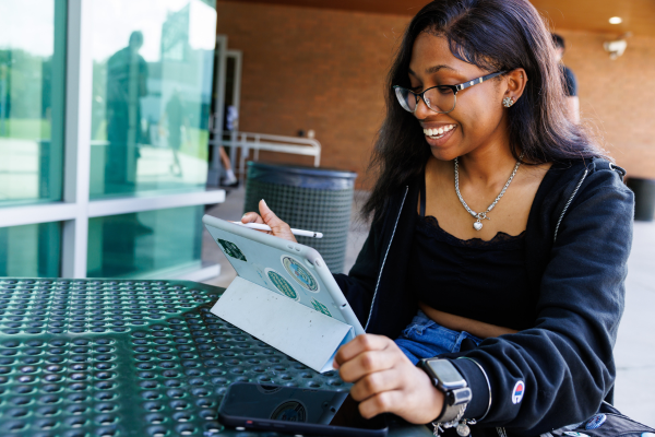 A student studying outdoors on her tablet