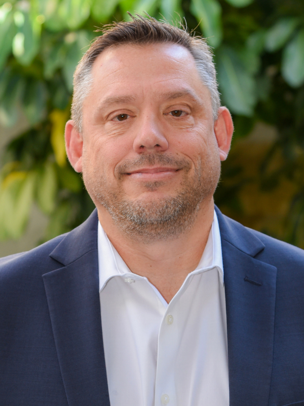 A headshot of Jay Evans smiling in an outdoor setting