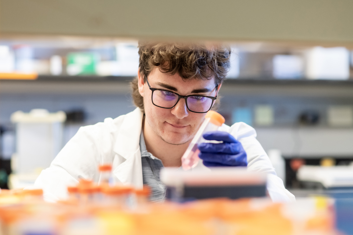 Medical professional wearing a white lab coat works in a laboratory with beakers