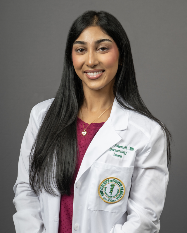 Anika Pulumati smiling wearing a burgundy blouse and a USF Health branded medical white coat