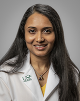 Dr. Swetangi smiling wearing a USF Health branded medical coat and a yellow blouse