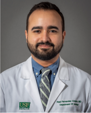 Dr. Fernandez-Crespo smiles wearing a USF Health medical white coat and multi-colored tie