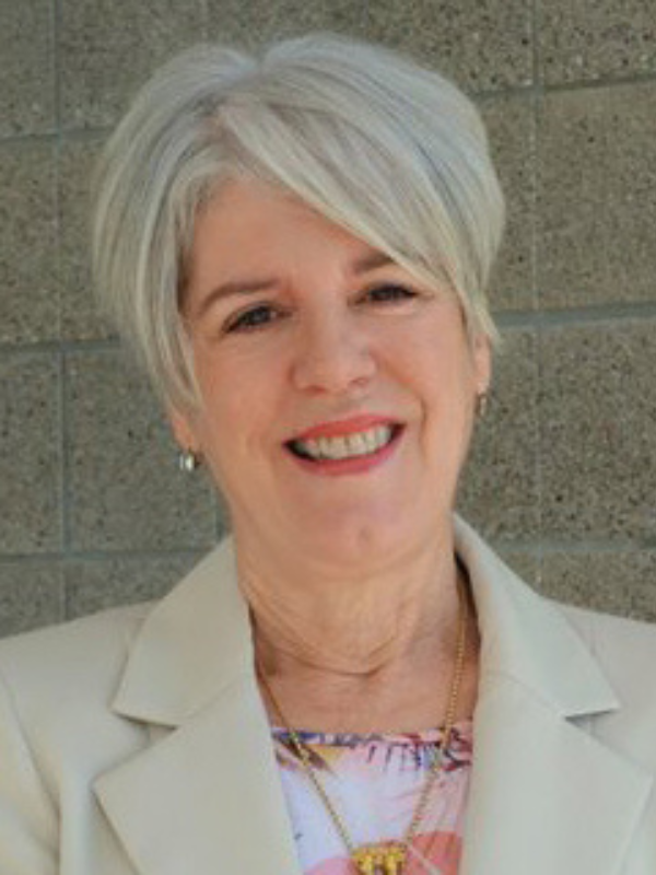 Headshot of Claudia Parvanta in front of a beige brick wall
