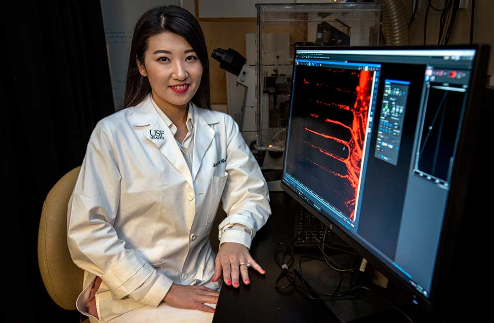 Dr. Alexa Woo sitting at a computer displaying medical chart information