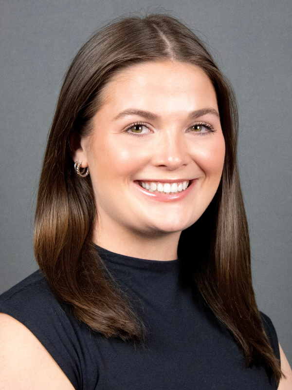 A headshot of Olivia Galler smiling in front of a grey backdrop.