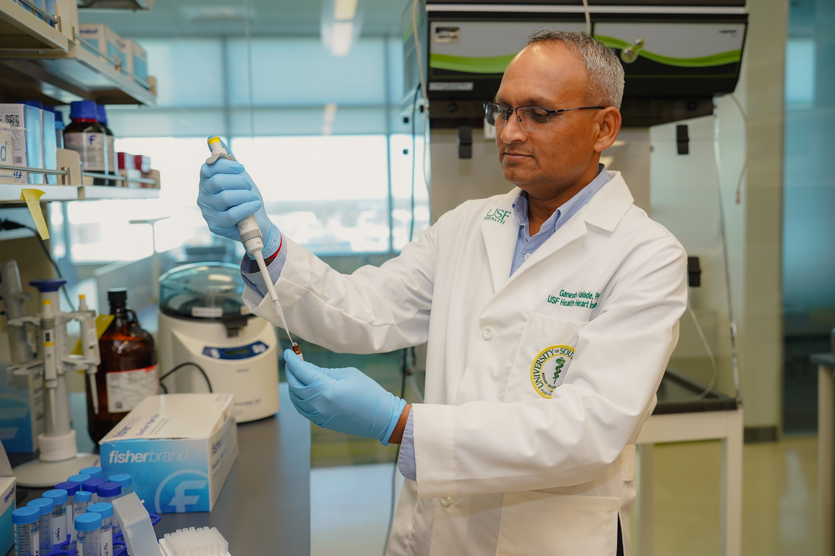 Dr. halade wearing a USF Health branded medical white coat in a medical lab