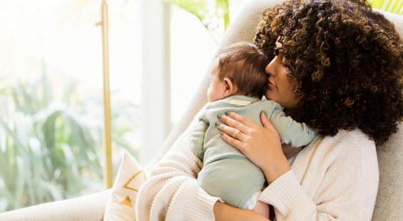 A mother sitting in a chair and holding her baby in her arms