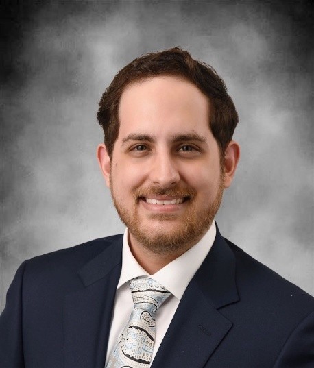 Marcos Gonzalez Perez smiling wearing a navy blue suit and silver and black striped tie