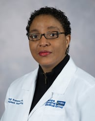 Nyingi Kemmer headshot smiling with a black blouse and medical white coat