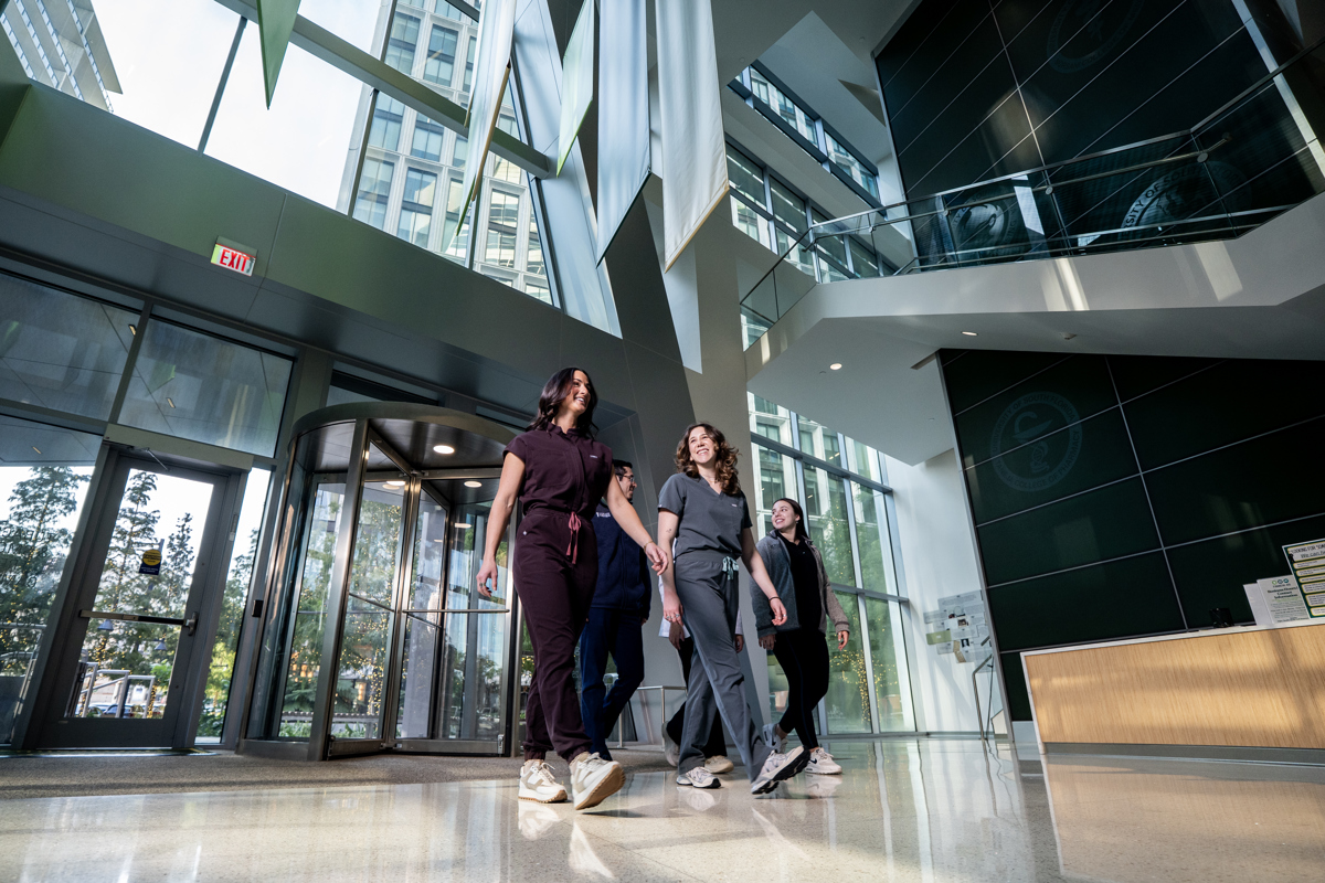 Four medical student walking through the lobby of USF Health downtown Tampa building wearing scrubs