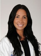 Alexandra smiles wearing a medical white coat and black blouse