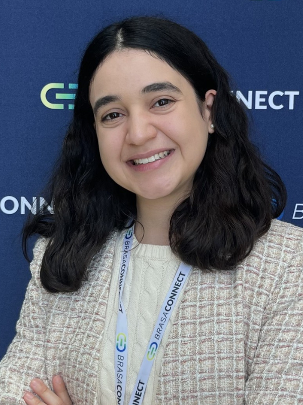 A headshot of Luiza Calixto De Oliveira smiling in front of a navy blue backdrop.