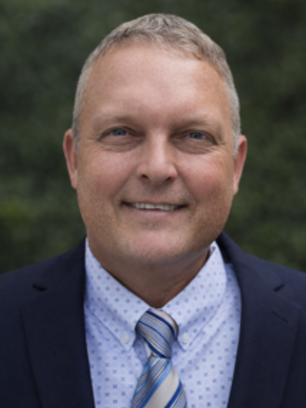 A headshot of Thomas Baase smiling in an outdoor setting